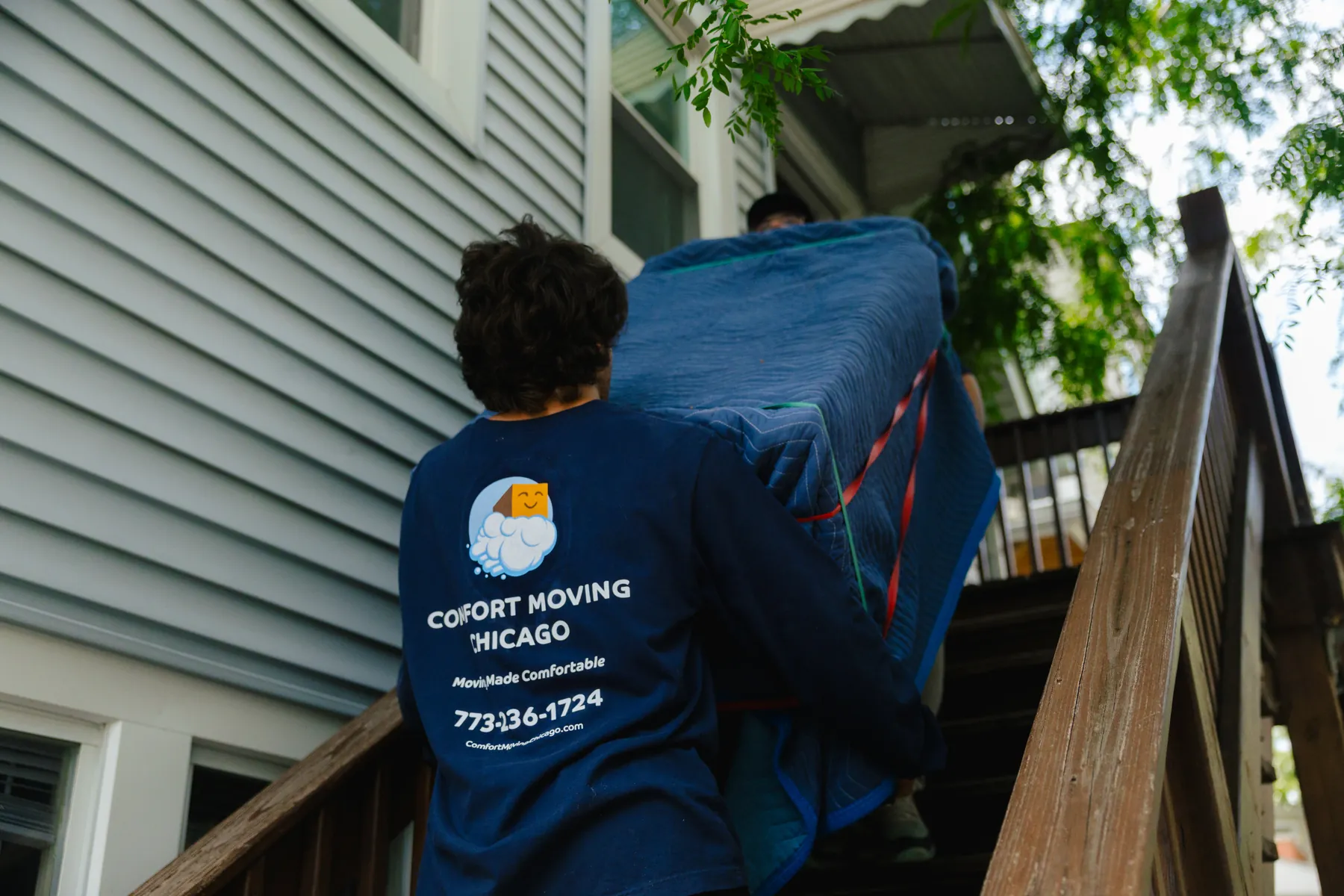 Comfort Moving Chicago movers carrying a blanket-wrapped couch up the back stairs of a Chicago walk-up apartment